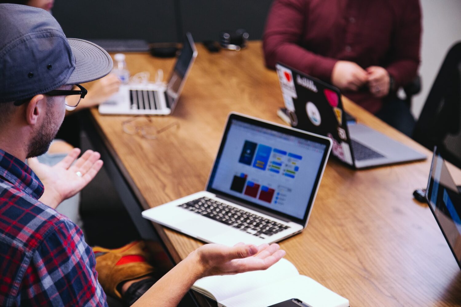 Man using laptop and gesturing in a meeting with others