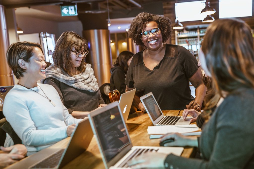 Group of women working at table with laptops